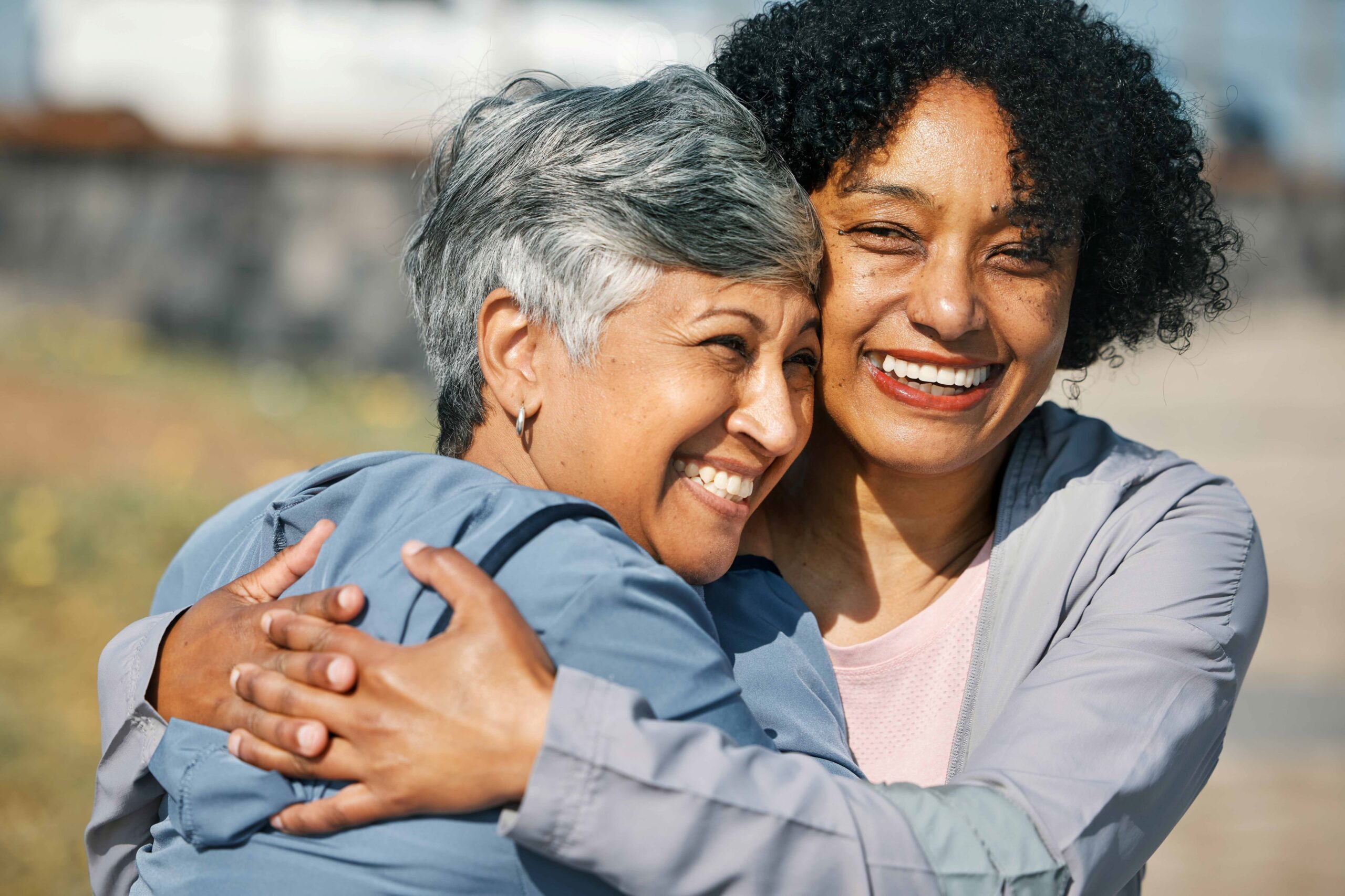 An elderly Asian Pacific Islander woman hugs her adult daughter who is her caregiver. They are outside as they assess what to look for in assisted living.